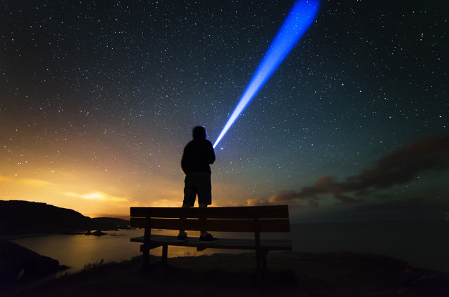 Spain, Ortigueira, Loiba, silhouette of a man standing on bench under starry sky with blue ray
Royalty free image
