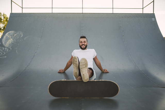 Smiling skateboarder sitting on ramp in a skatepark
Royalty free image