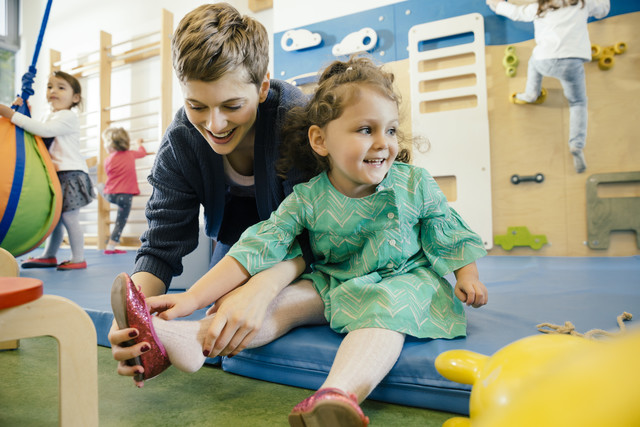 Pre-school teacher helping little girl putting a shoe on Royalty free image Pre-school teacher helping little girl putting a shoe on
Royalty free image