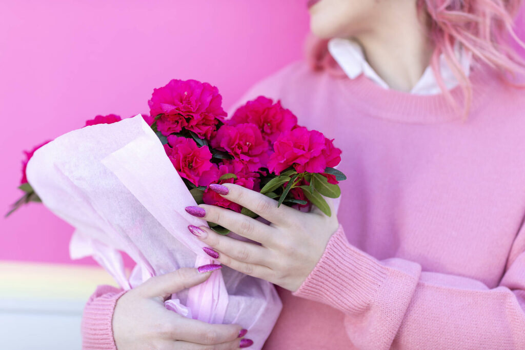 stock image, royalty-free, Young woman with pink hair and jumper holding bunch of azaleas flowers; Florence, Tuscany, Italy