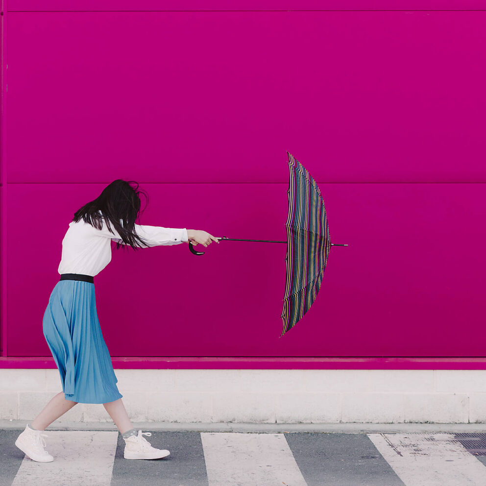 stock image, royalty-free, Young woman holding umbrella in front of a pink wall