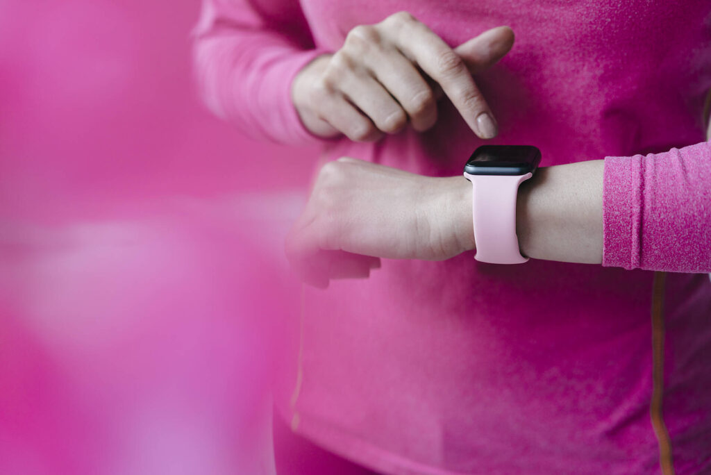 stock image, royalty-free, Close-up of woman in pink sportswear adjusting her smartwatch