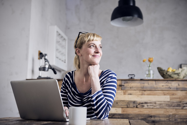 Stockfoto, lizenzfrei, Porträt einer lächelnden Frau am Tisch sitzend mit Laptop und Kaffeetasse