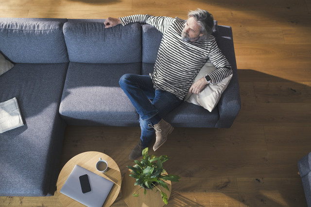 Stockfoto, lizenzfrei, Älterer Mann sitzt auf dem Sofa, entspannt sich und denkt