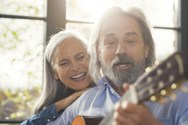 Stockfoto, lizenzfrei, Senior spielt Gitarre und singt laut für seine Frau
