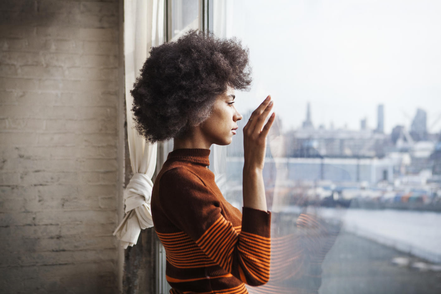 Side view of woman looking though window at home
Royalty free image