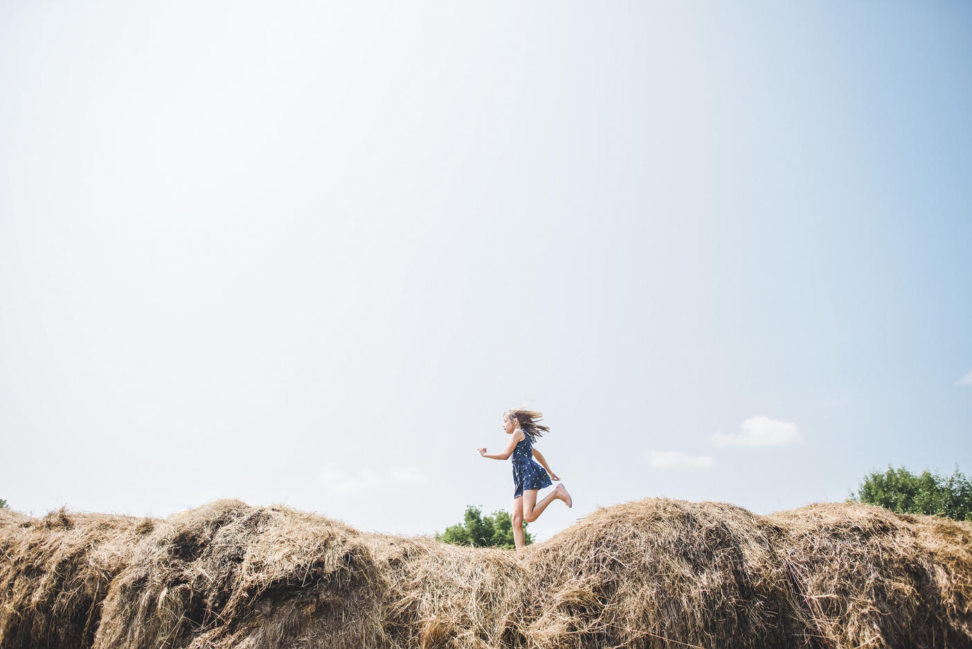 Carefree girl running on heap of hay against sky
Royalty free image