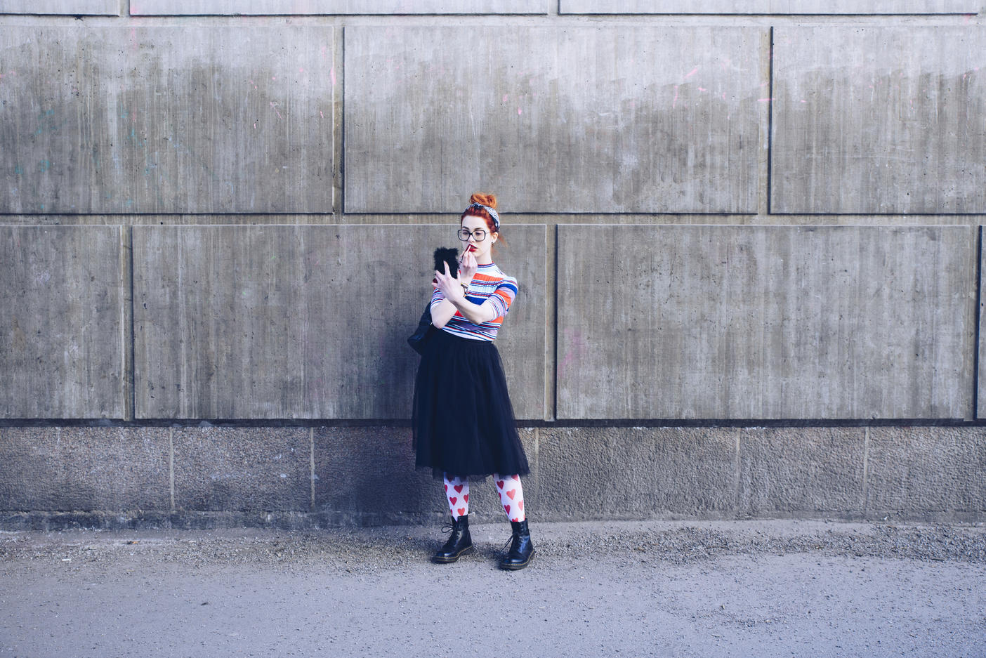 Young woman looking at mobile phone while applying lipstick against wall Royalty free image Young woman looking at mobile phone while applying lipstick against wall
Royalty free image