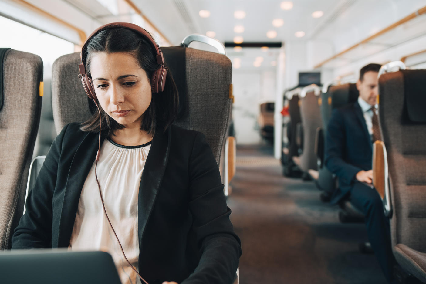 Mid adult businesswoman using headphones and laptop while traveling in train Royalty free image Mid adult businesswoman using headphones and laptop while traveling in train
Royalty free image
