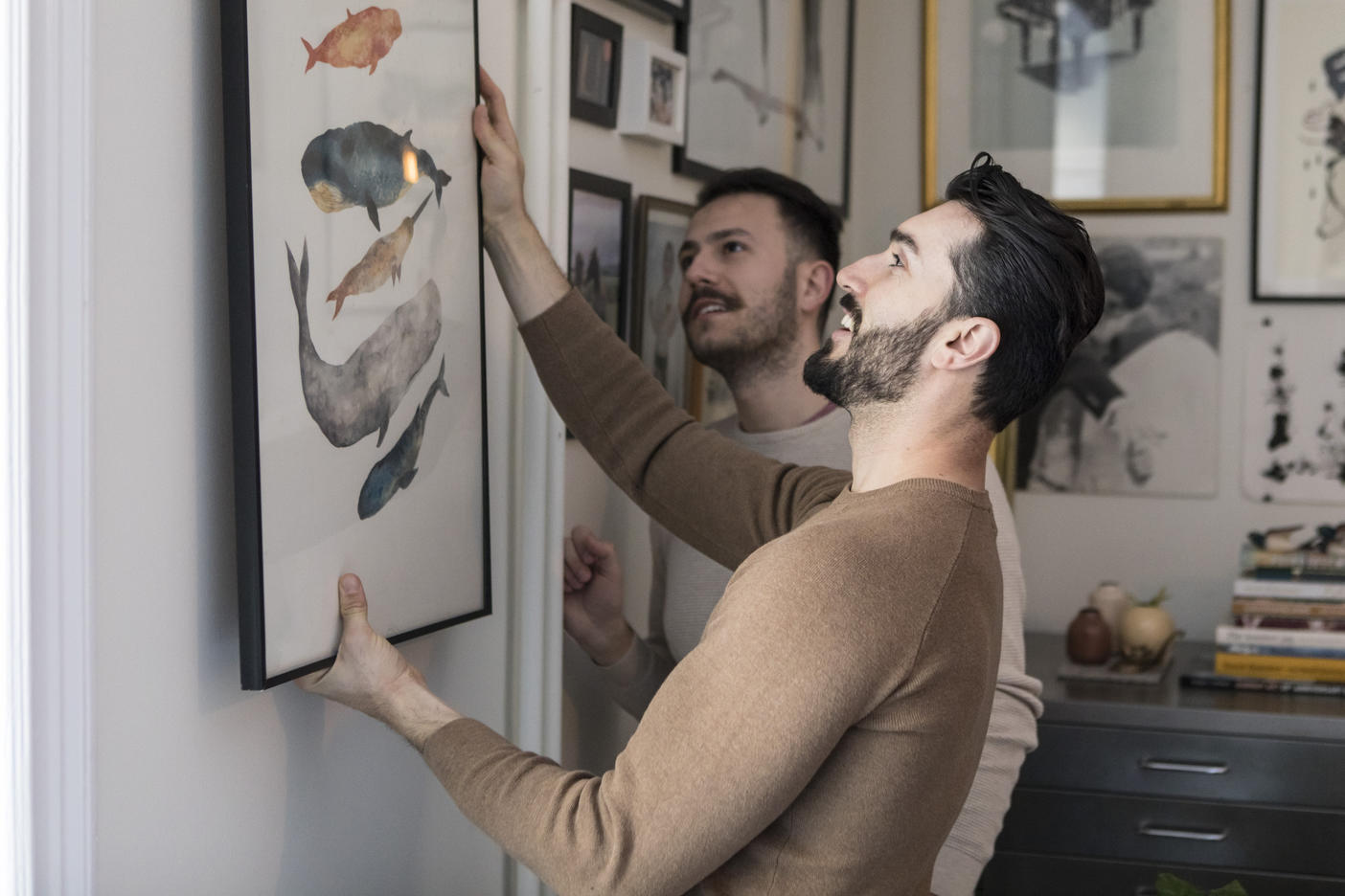 Homosexual couple hanging painting on wall at home Royalty free image Homosexual couple hanging painting on wall at home
Royalty free image