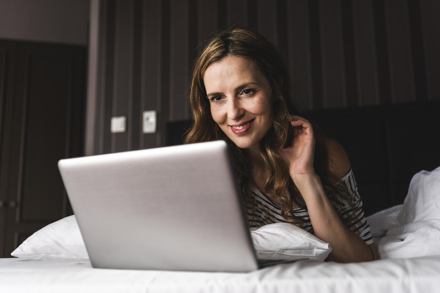 Smiling woman lying on bed at home looking at laptop
Royalty free image
