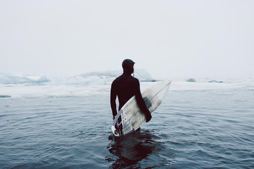 Man carrying surfboard while standing in icy sea against clear sky during winter
Royalty free image