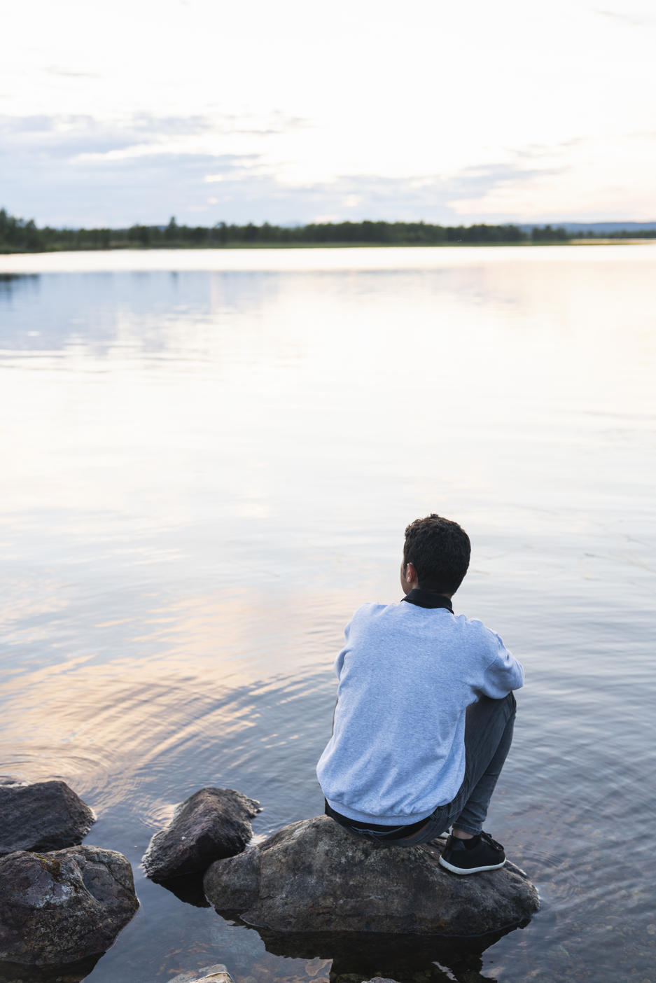 Finland, Lapland, man sitting on a rock in a lake Royalty free image Finland, Lapland, man sitting on a rock in a lakeRoyalty free image