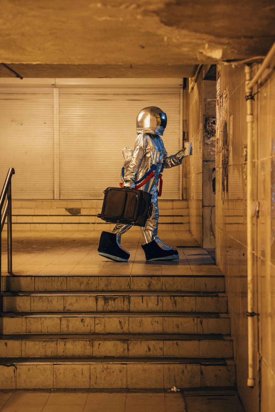 Spaceman in the city at night walking in underpass with suitcase and takeaway coffee
Royalty free image