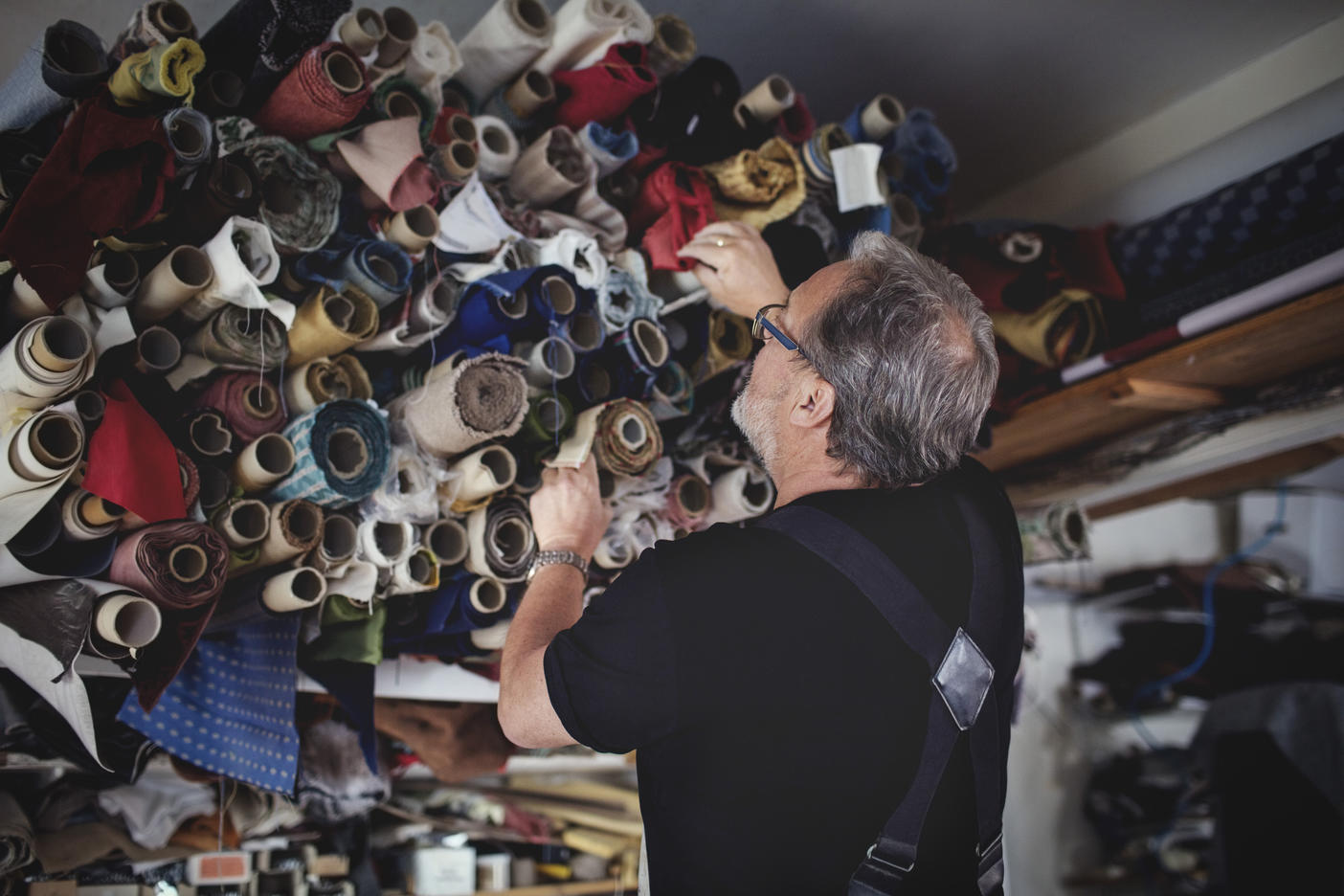 Low angle view of senior male owner looking at rolled fabrics in workshop
Royalty free image