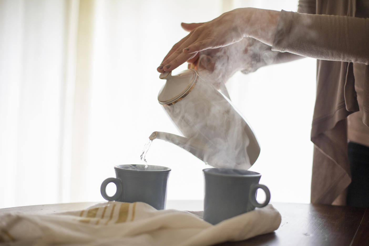 Close up of a woman pouring hot water from a coffee pot into a mug.
Royalty free image
