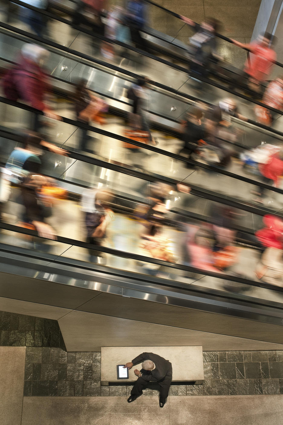 Businessman on a notebook computer near an escalator full of people.
Royalty free image