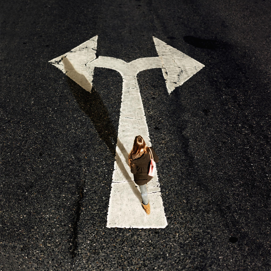 Woman walking on directional arrow of a road
Royalty free image