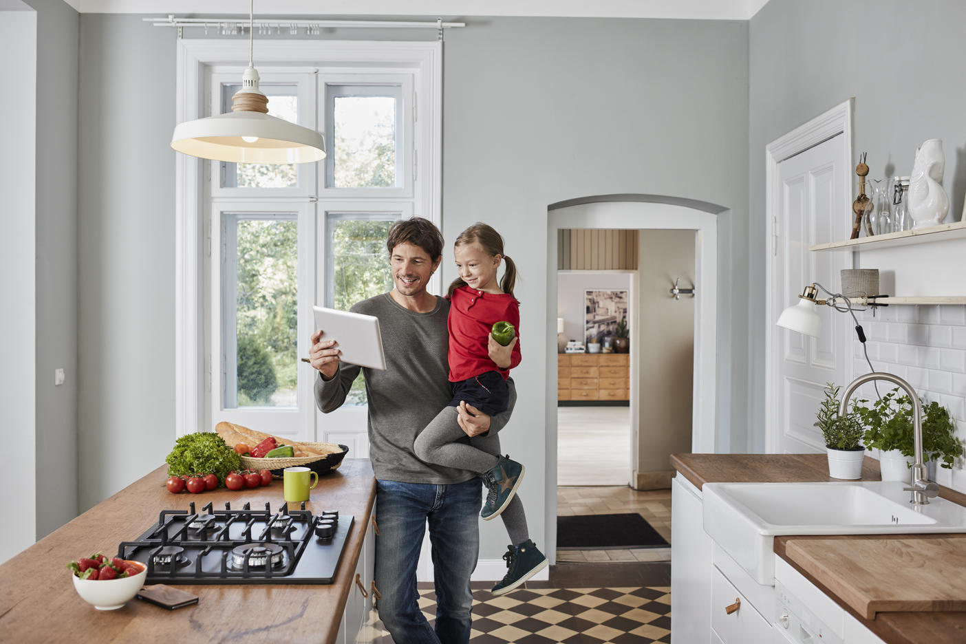 Happy father and daughter with bell pepper and tablet in kitchenRoyalty free image