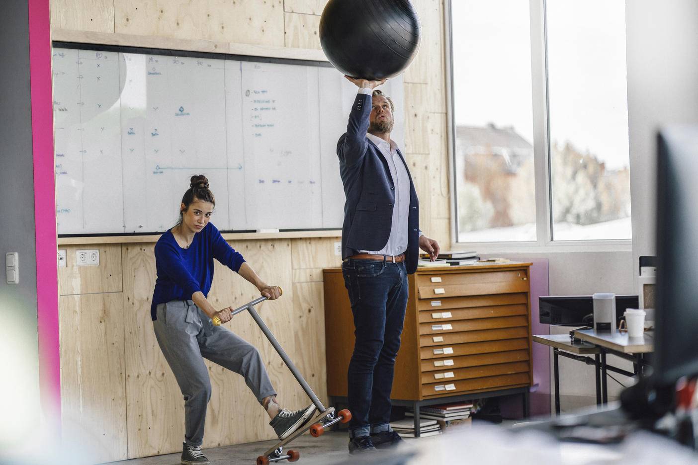 Mature man and his assistent playing with scooter, standing in office in front of white board
Royalty free image