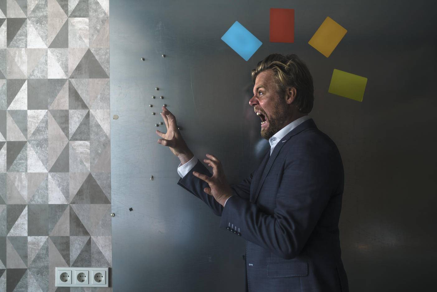 Businessman standing in front of magnet wall with a colorful headdress, made from sticky notes, roaring
Royalty free image