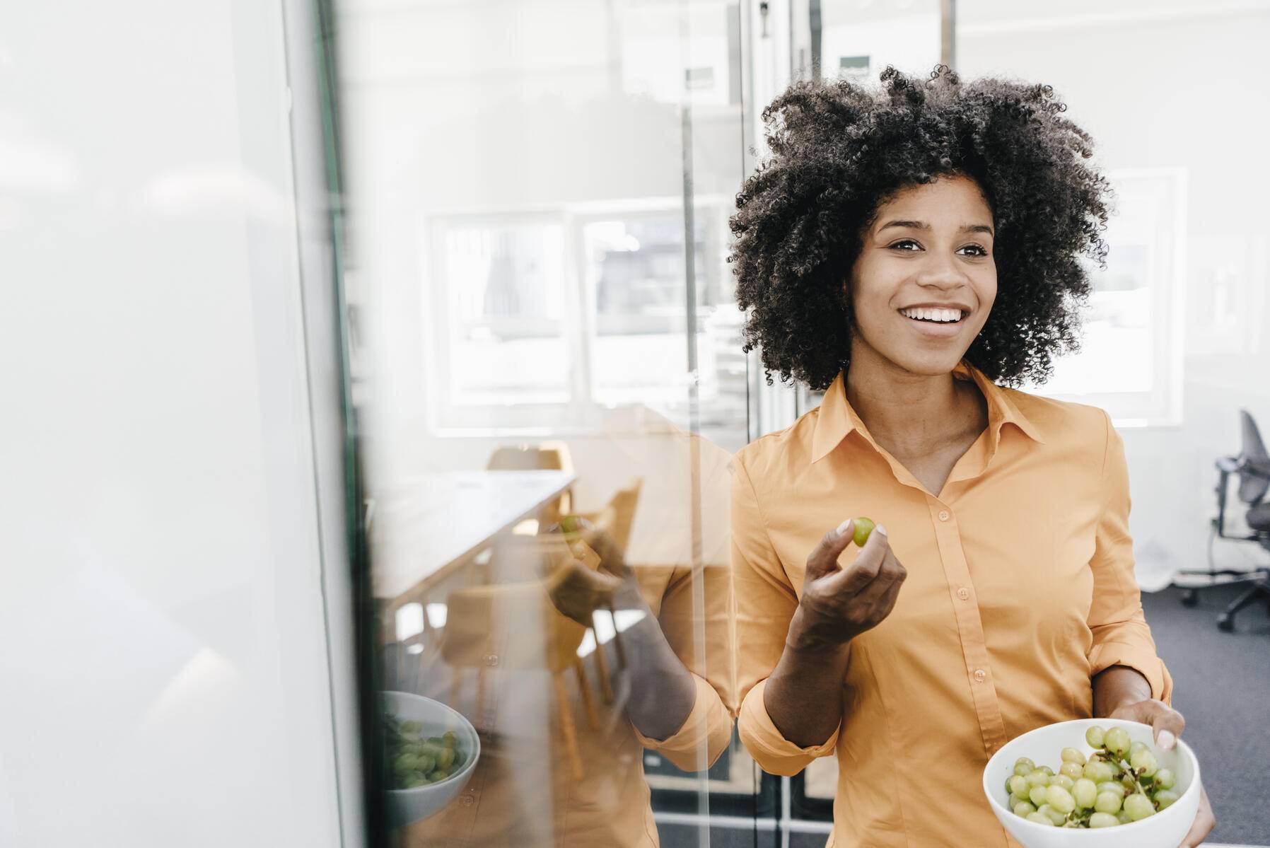 Smiling young woman holding bowl with grapes in office
Royalty free image