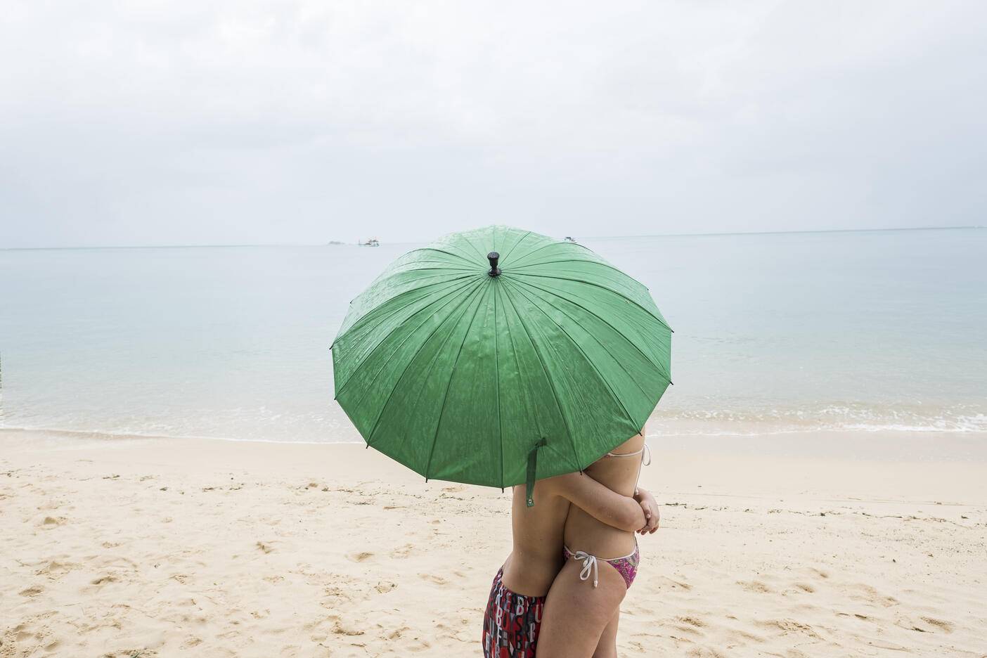 Thailand, boy hugging his mother on the beach under a green umbrella
Royalty free image