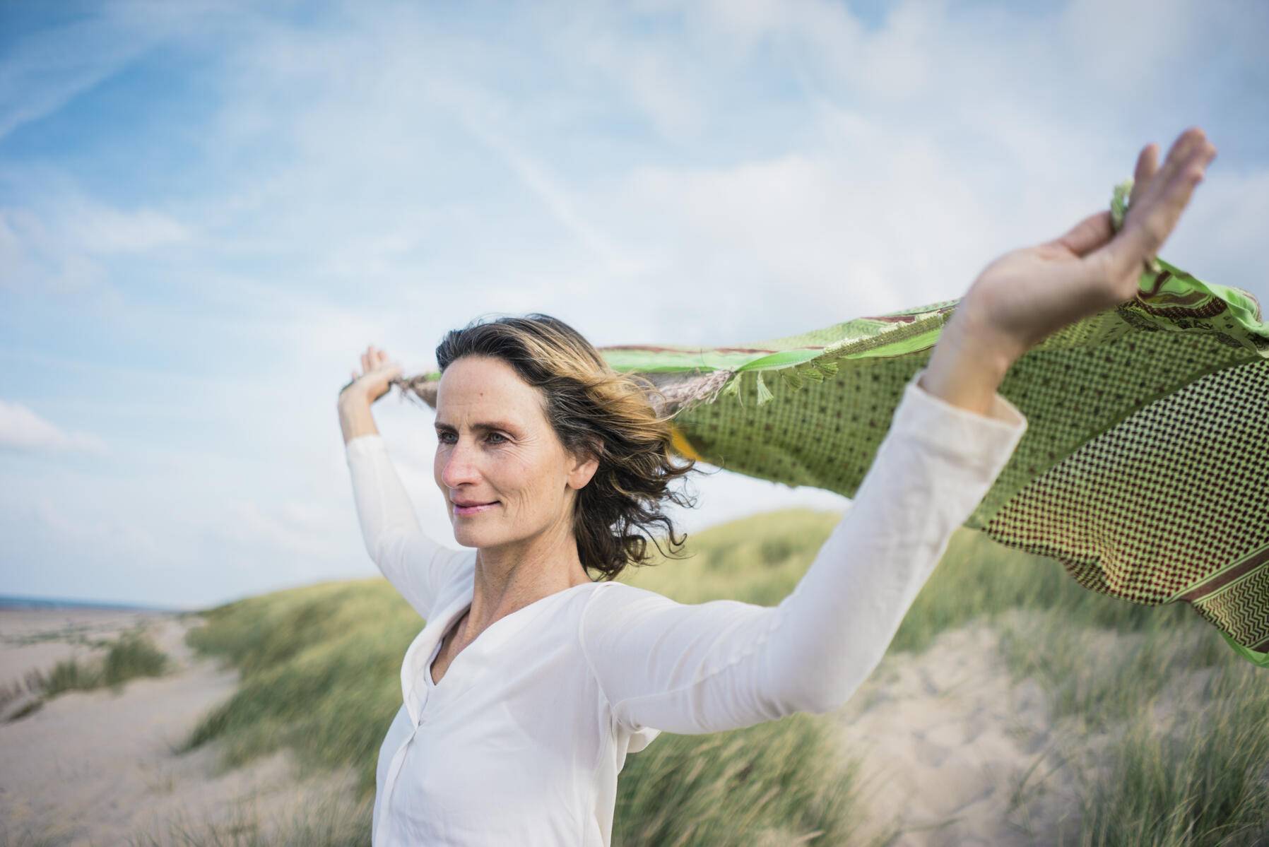Mature woman holding flapping scarf in the wind, relxiang in the dunes
Royalty free image