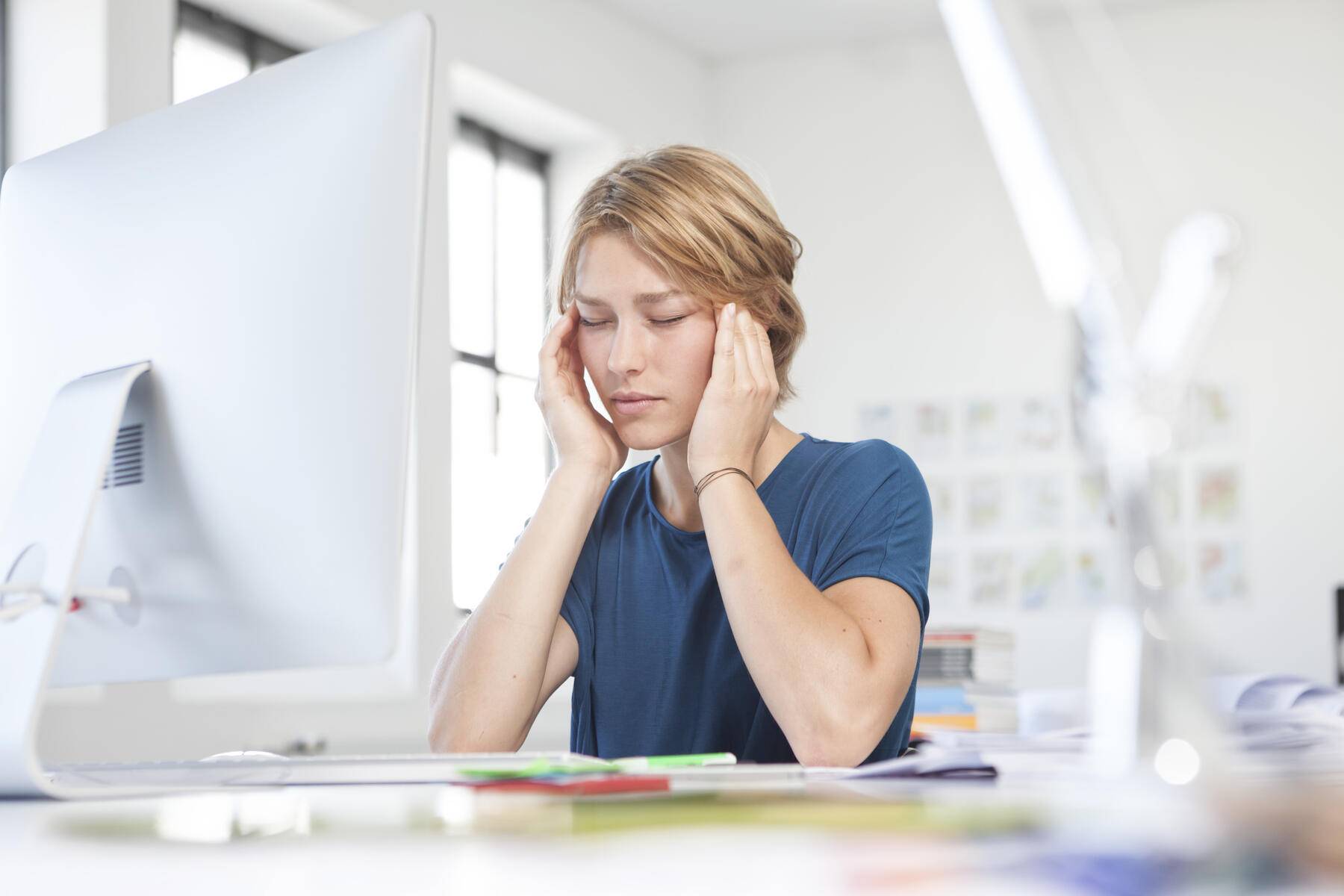 Portrait of young woman with headache at her desk in a creative office
Royalty free image