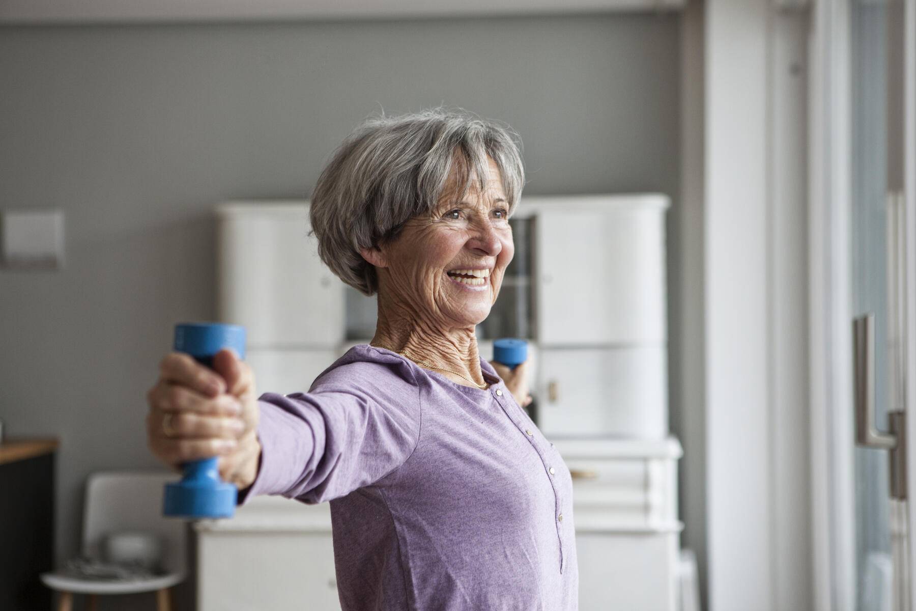 Portrait of happy senior woman doing fitness exercise with dumbbells at home
Royalty free image