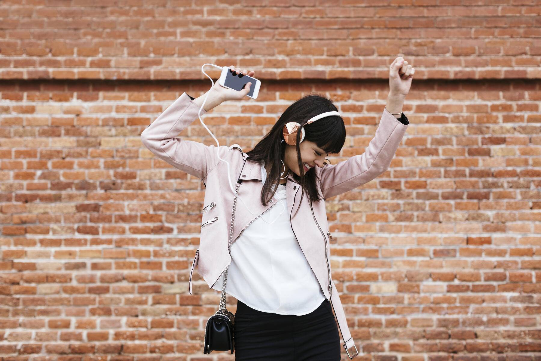 Happy woman with cell phone listening to music on headphones at brick wall Royalty free image Happy woman with cell phone listening to music on headphones at brick wall
Royalty free image