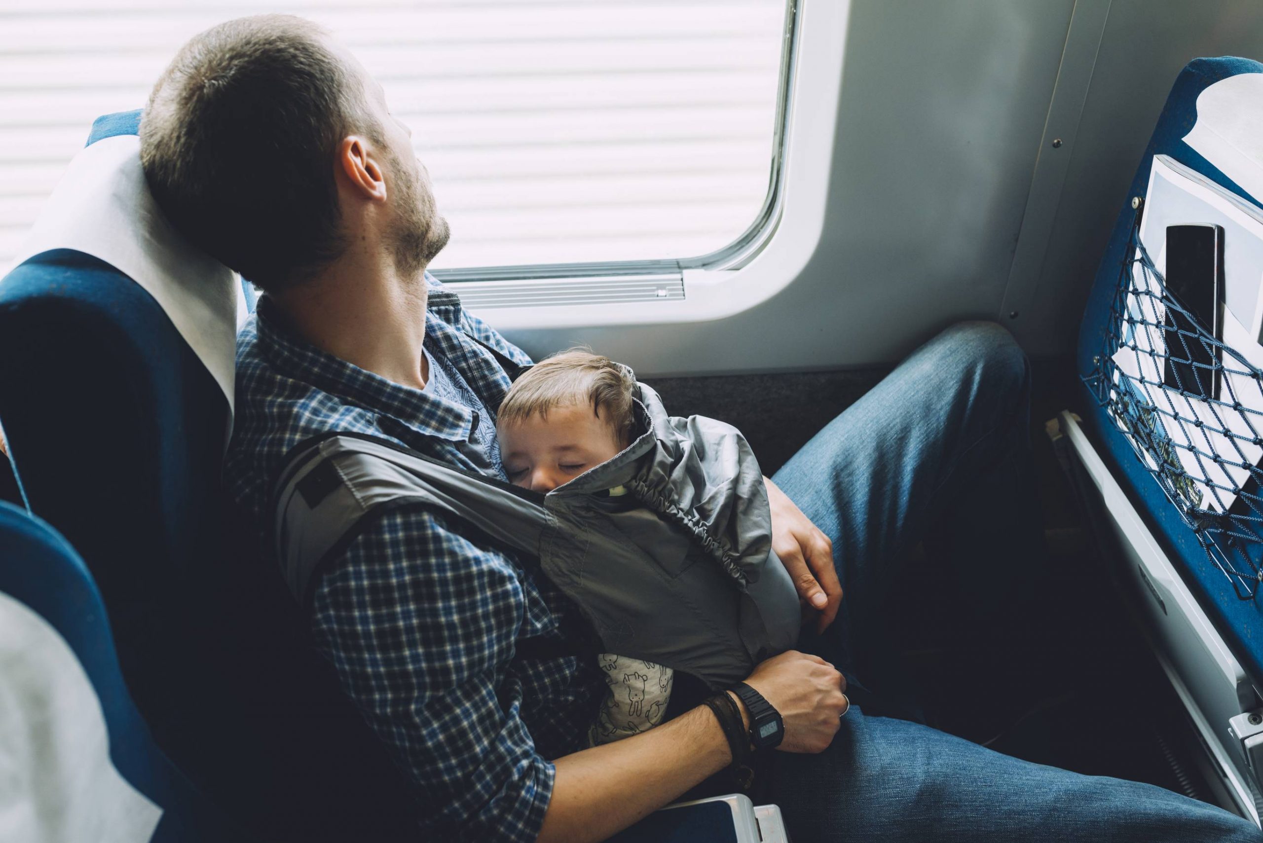 Father on the train holding his sleeping baby in a baby carrier
Royalty free image