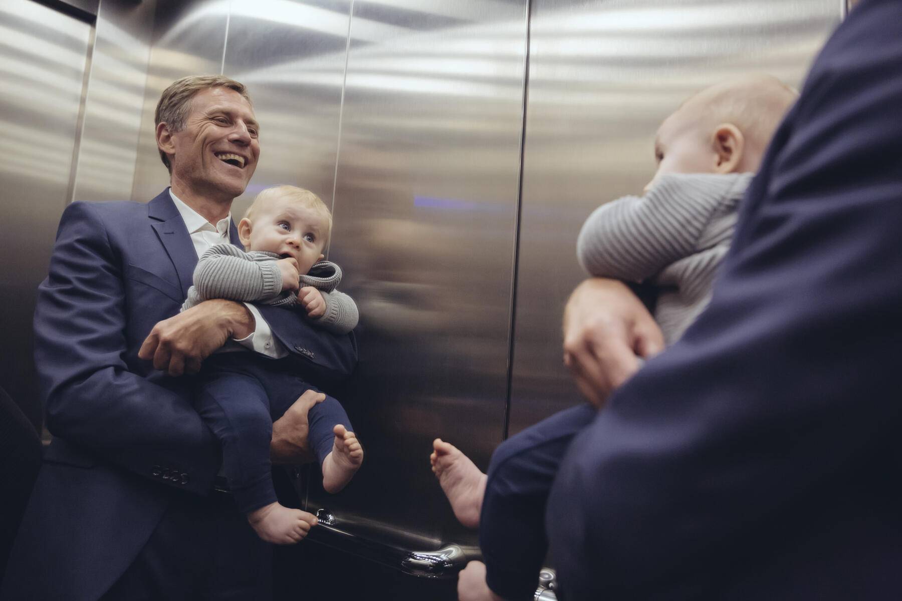 Happy mature businessman holding baby boy looking in mirror in elevator
Royalty free image