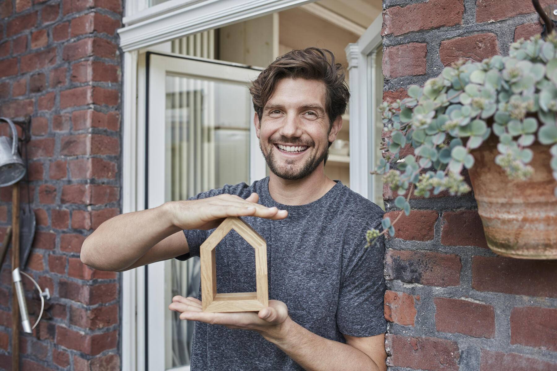 Portrait of smiling man at house entrance holding house model
Royalty free image