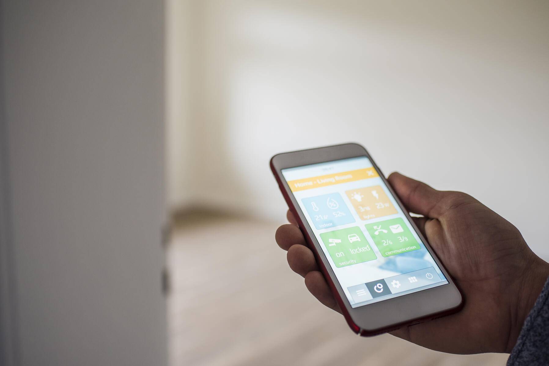 Man at home holding smartphone with smart home apps Royalty free image Man at home holding smartphone with smart home apps
Royalty free image