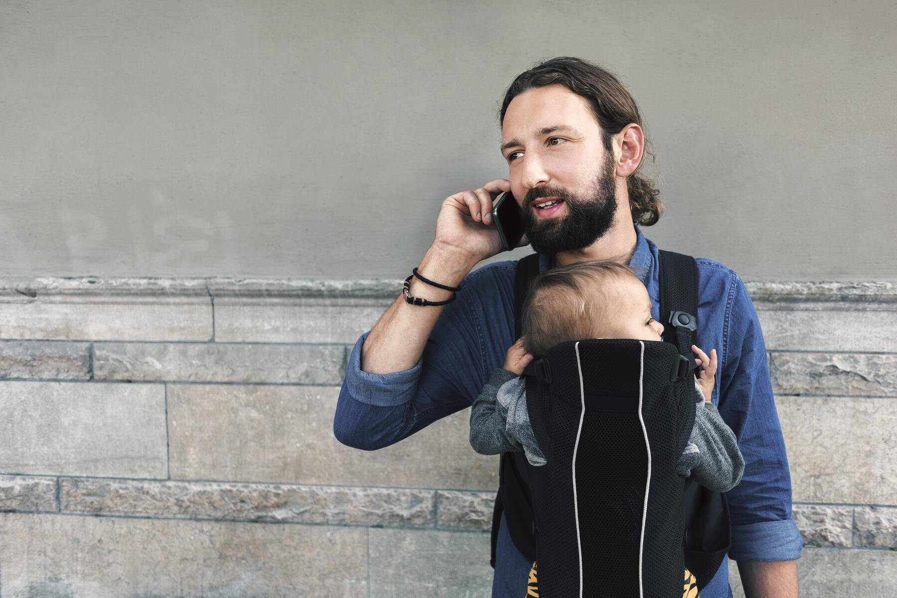 Mid adult man using mobile phone while carrying son in baby carrier against wall
Royalty free image