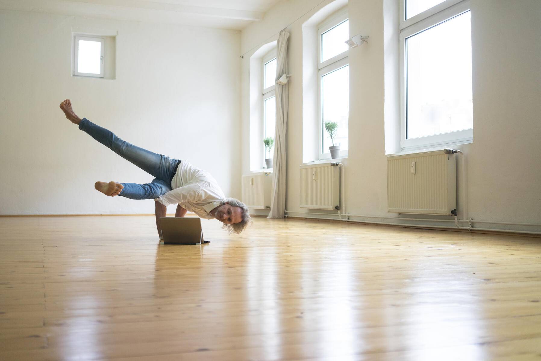Mature man doing a handstand on floor in empty room looking at tablet
Royalty free image