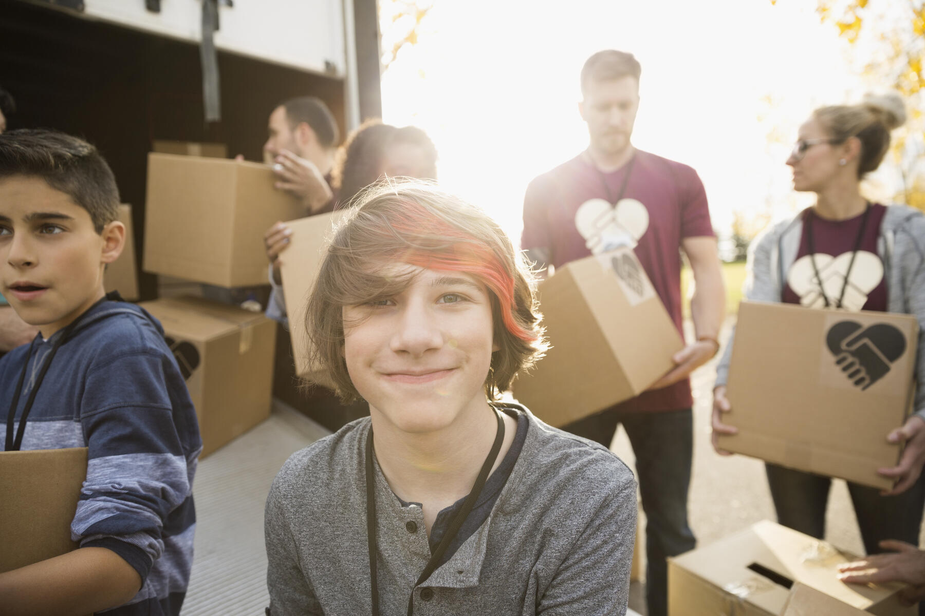 royalty-free, stock image, Portrait smiling tween boy volunteering helping unload cardboard boxes from truck