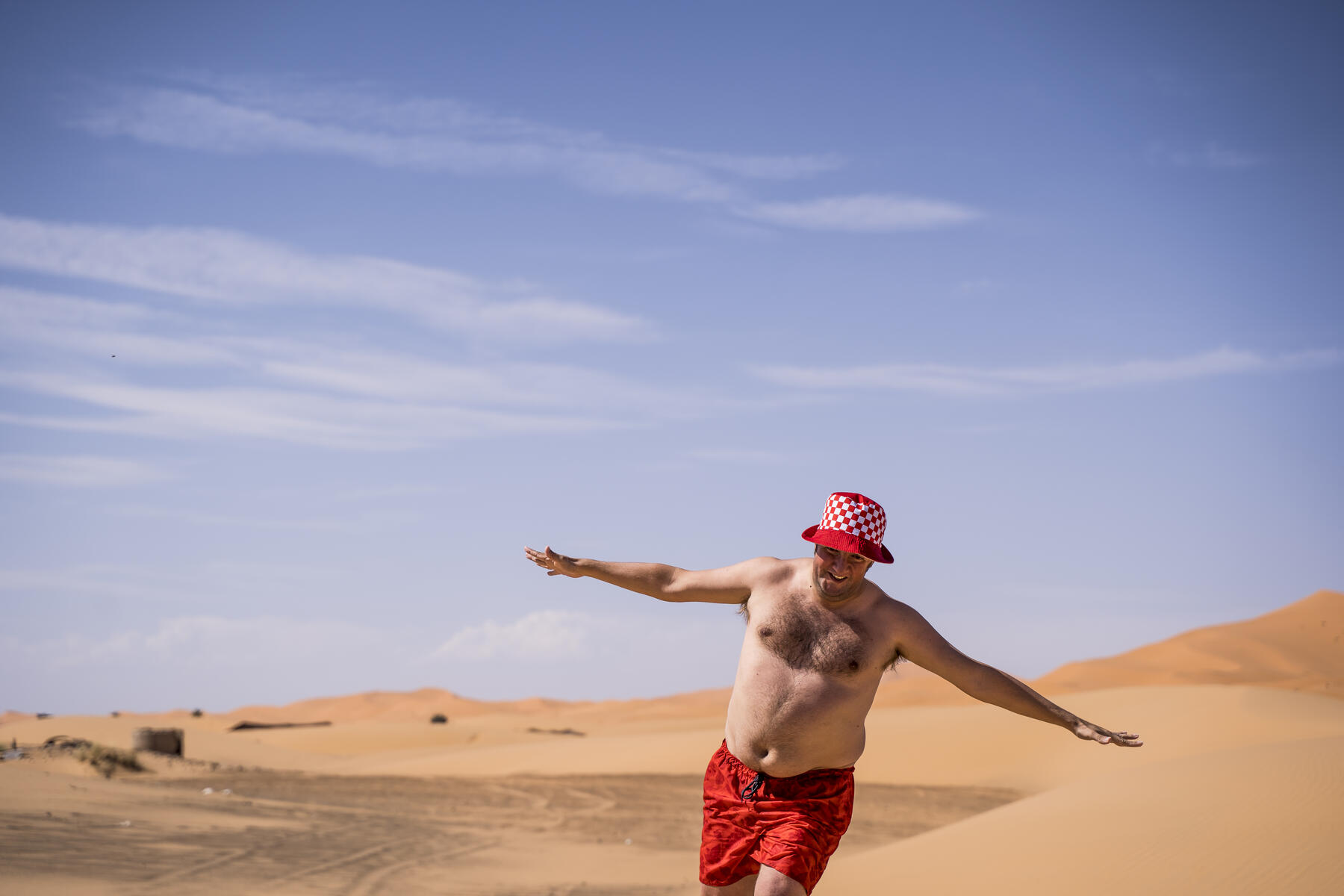 stock image, royalty-free, Happy overweight man with swimming shorts running in the desert of Morocco