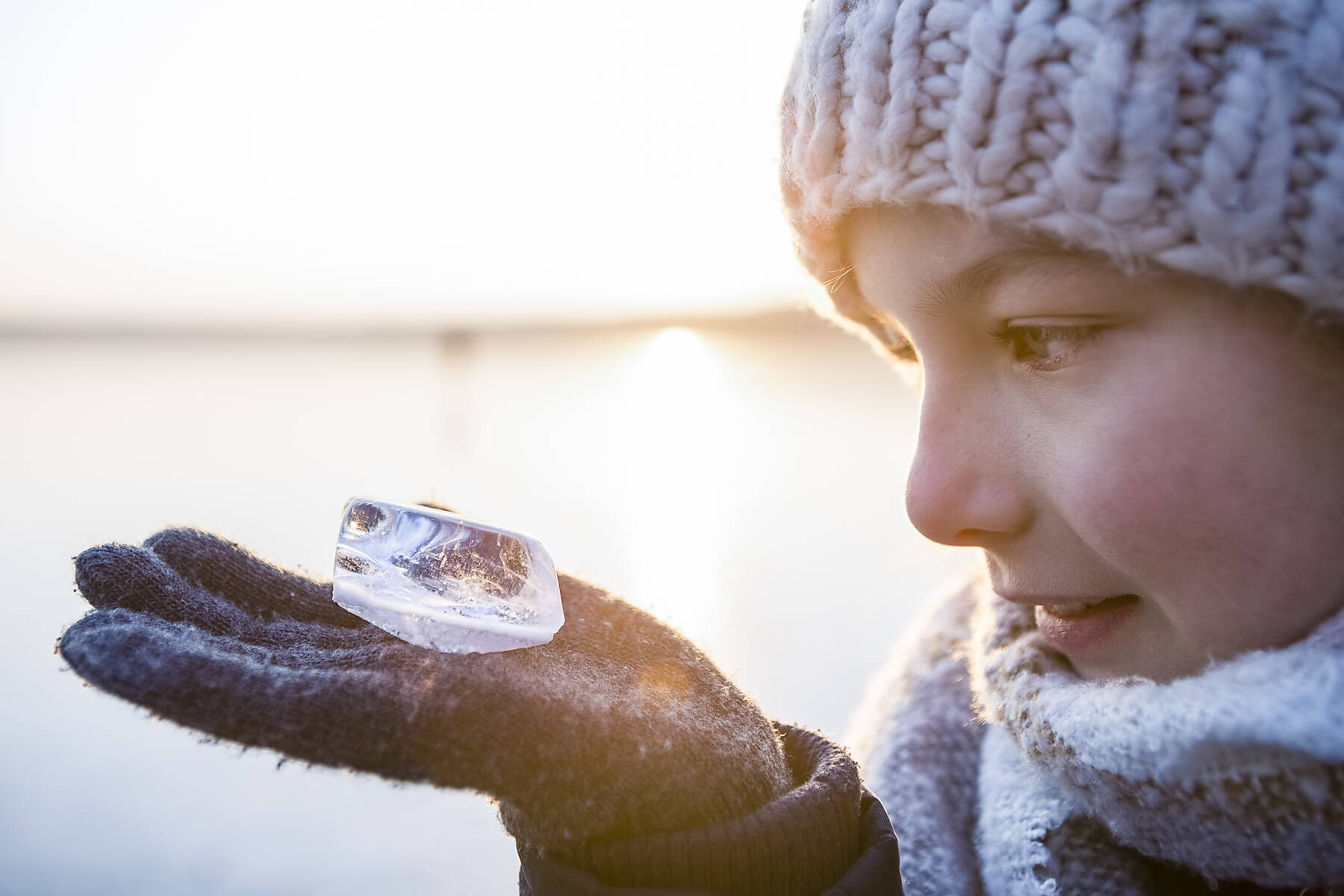 Stock image, royalty-free, Germany, Brandenburg, Lake Straussee, portrait of a girl standing on frozen lake, looking at piece of ice on her hand