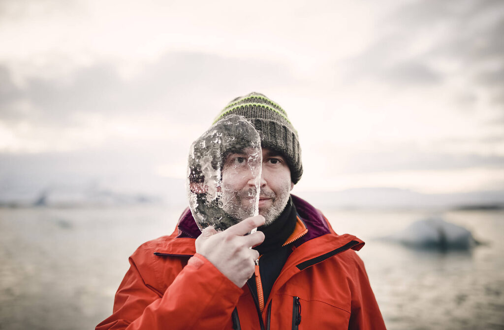 stockfoto, Island, erwachsener Mann mit einem Stück Eis, das sein halbes Gesicht bedeckt.