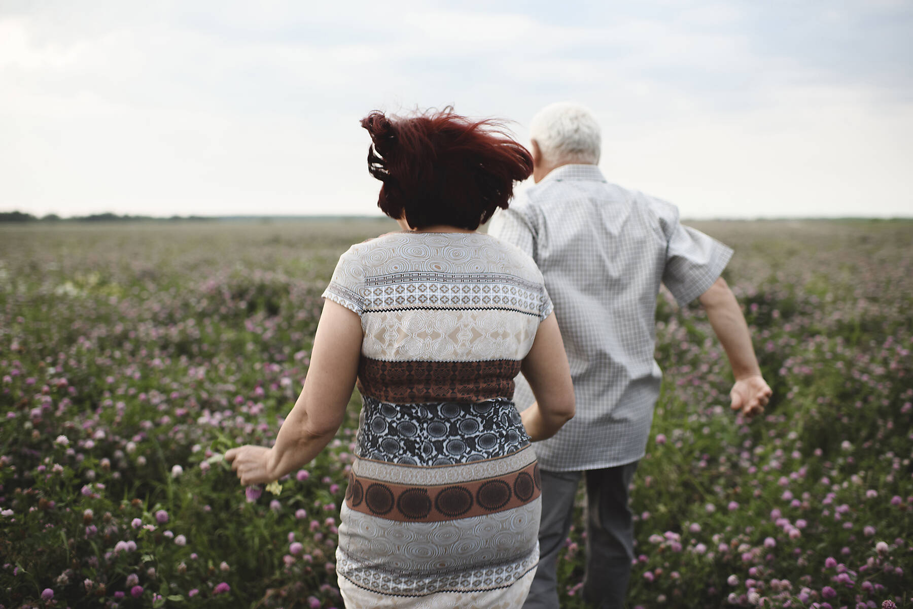 stock image, royalty-free, Back view of senior couple running on flower meadow