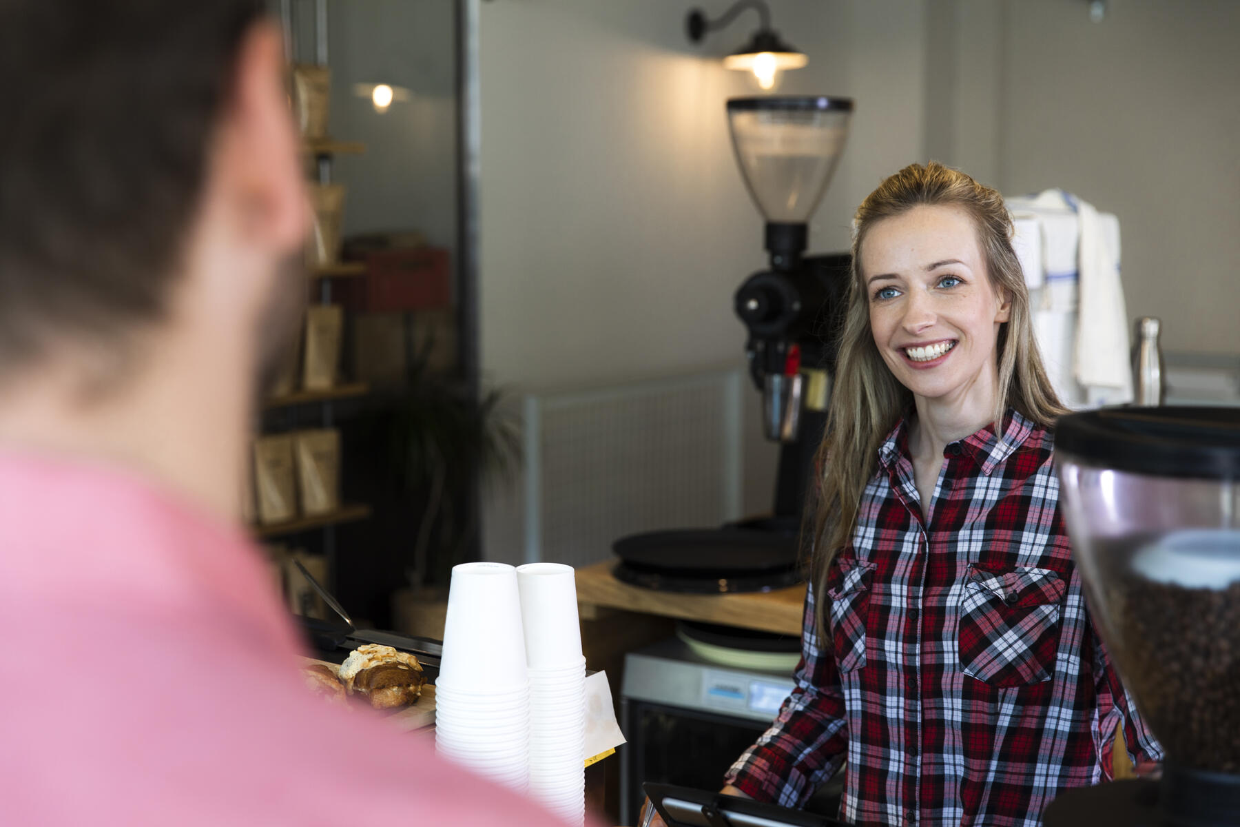 stock image, royalty-free, Smiling woman at counter in a cafe looking at man