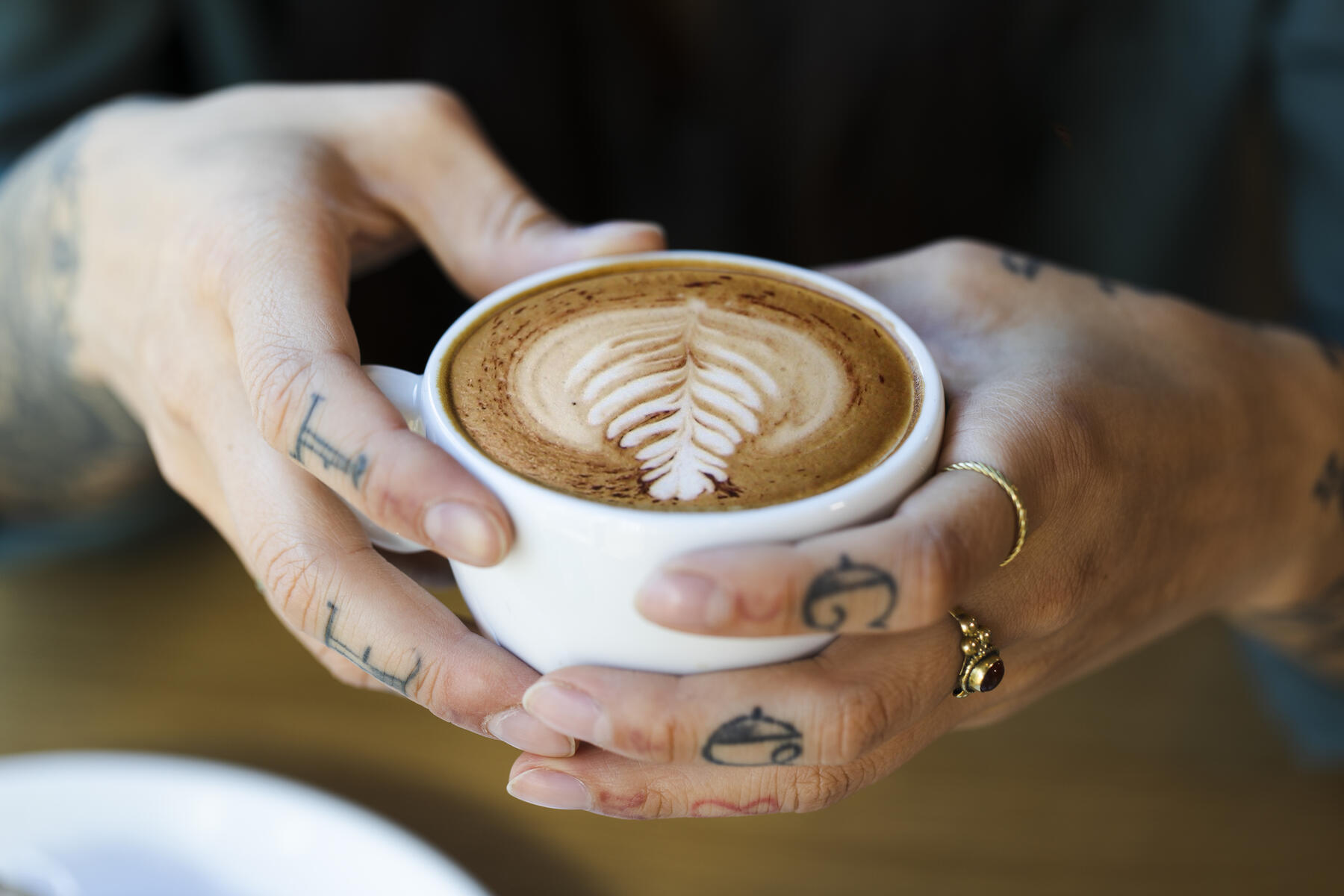 Stock image, royalty-free, Tattooed hands holding cup of cappuchino