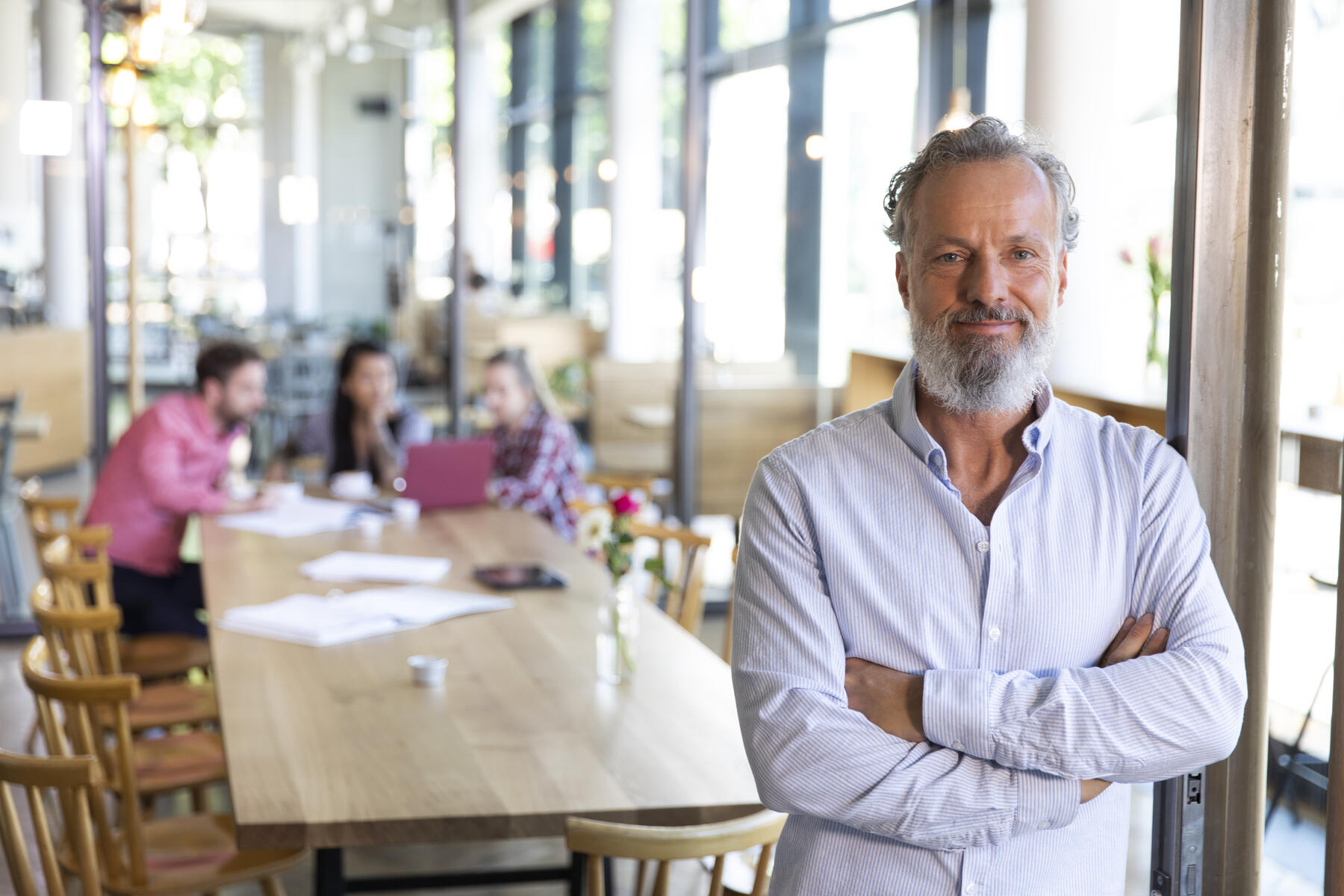 stock image, royalty-free, Portrait of mature businessman in a cafe with colleagues having a meeting in background