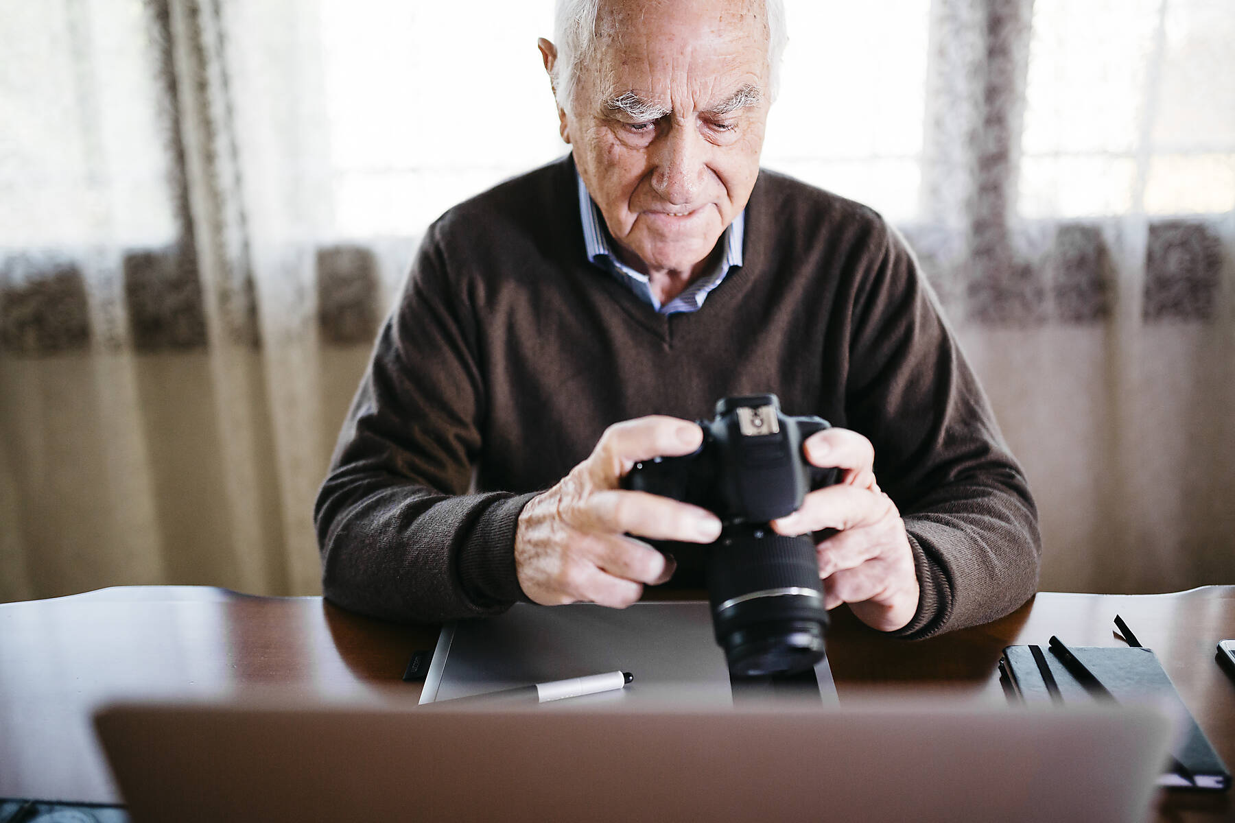 stockfoto, lizenzfrei, Senior-Fotograf mit Laptop und Digitalkamera zu Hause