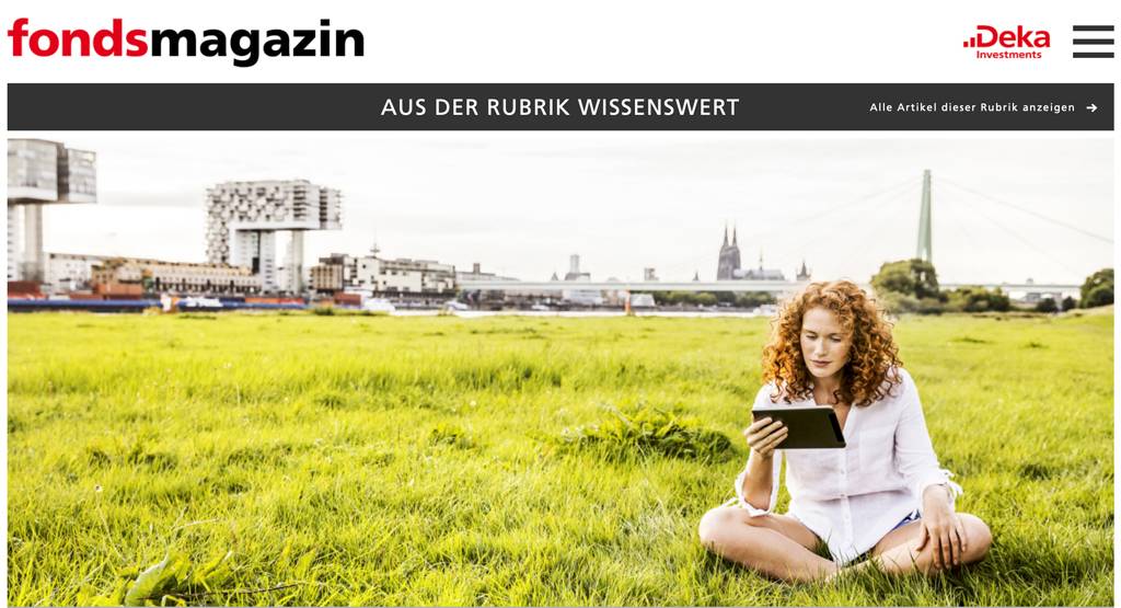 Germany, Cologne, young woman sitting on meadow looking at tablet - FMKF04384