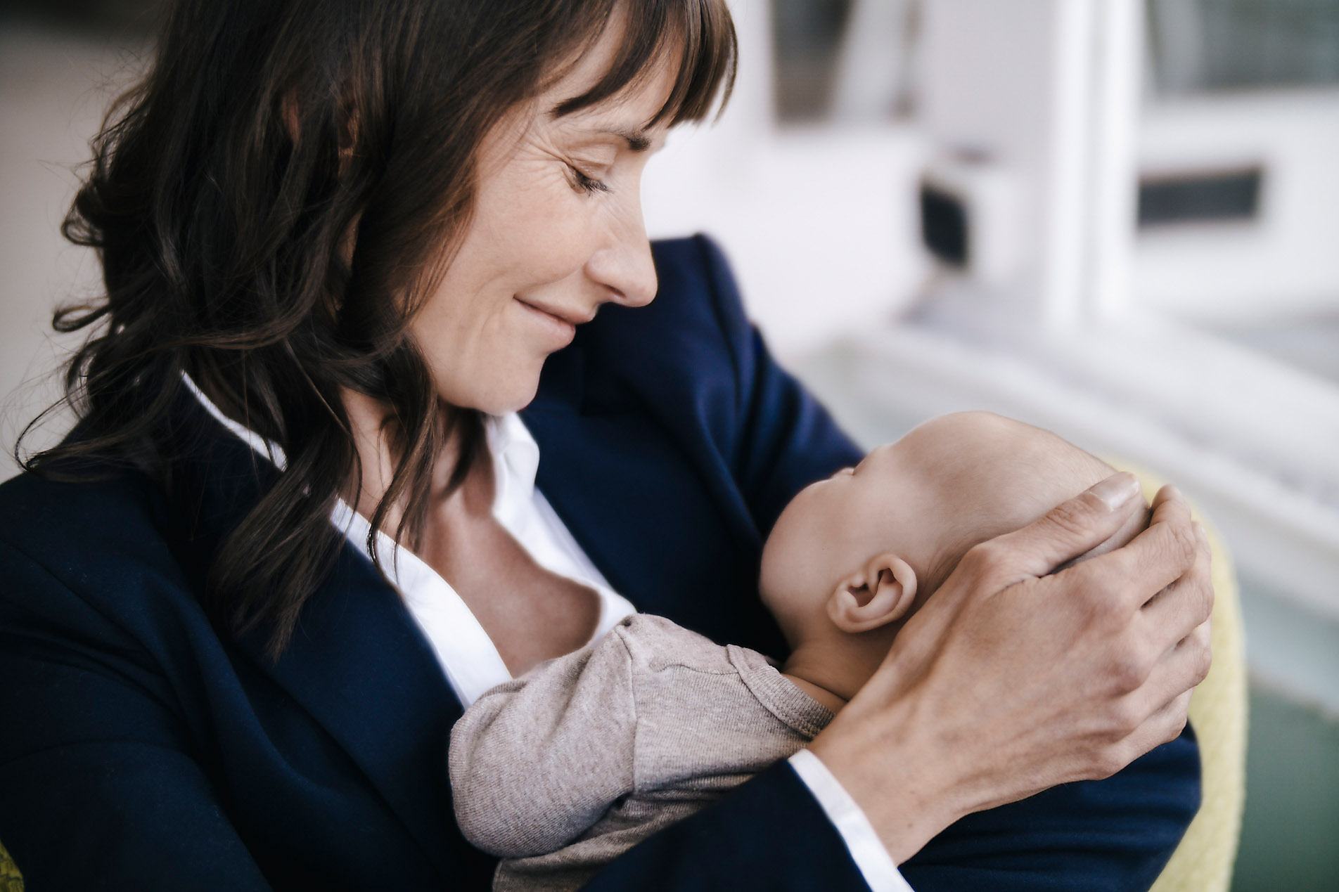 Businesswoman in cafe holding sleeping baby, stock image, royalty-free, security, safety, family