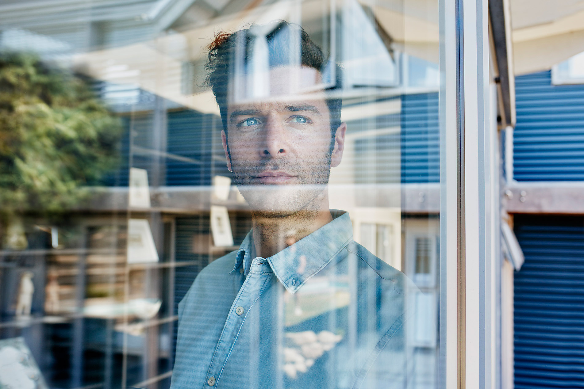 Portrait of young man standing behind glass looking outside, stock photo, royalty free, Westend61, security, protection