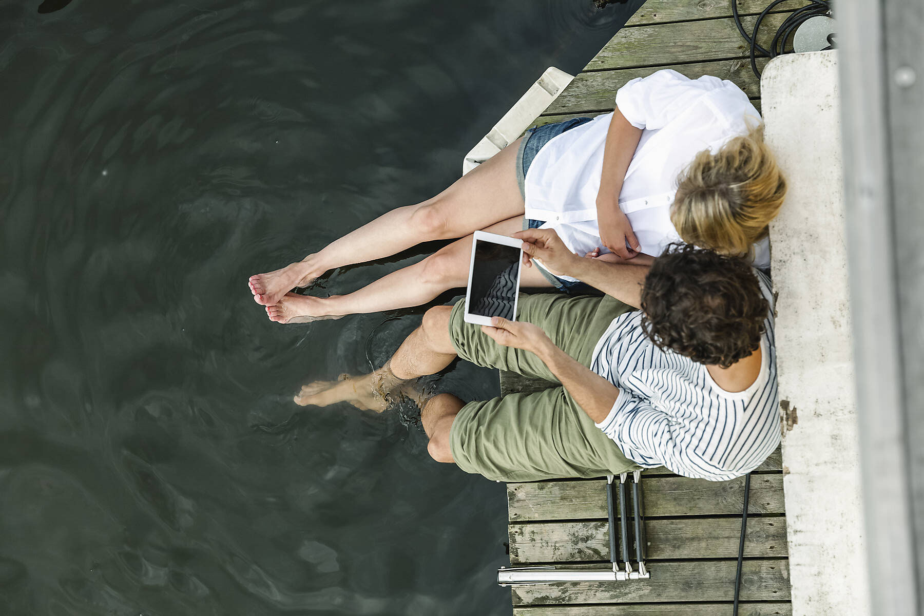 stockfoto, Gemeinsame Nutzung digitaler Tabletts durch Ehepaare am Wasser